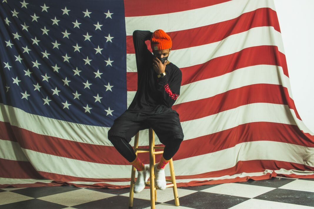 man on stool in front of American flag