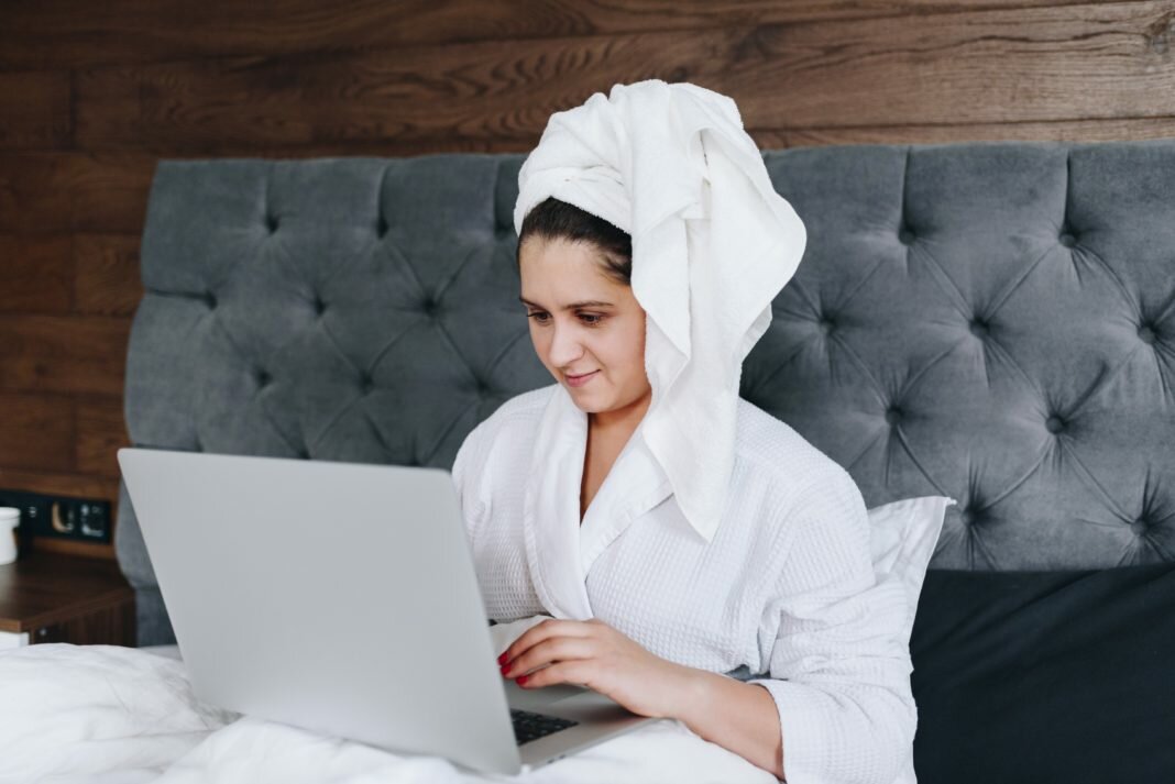 man in robe on bed with laptop