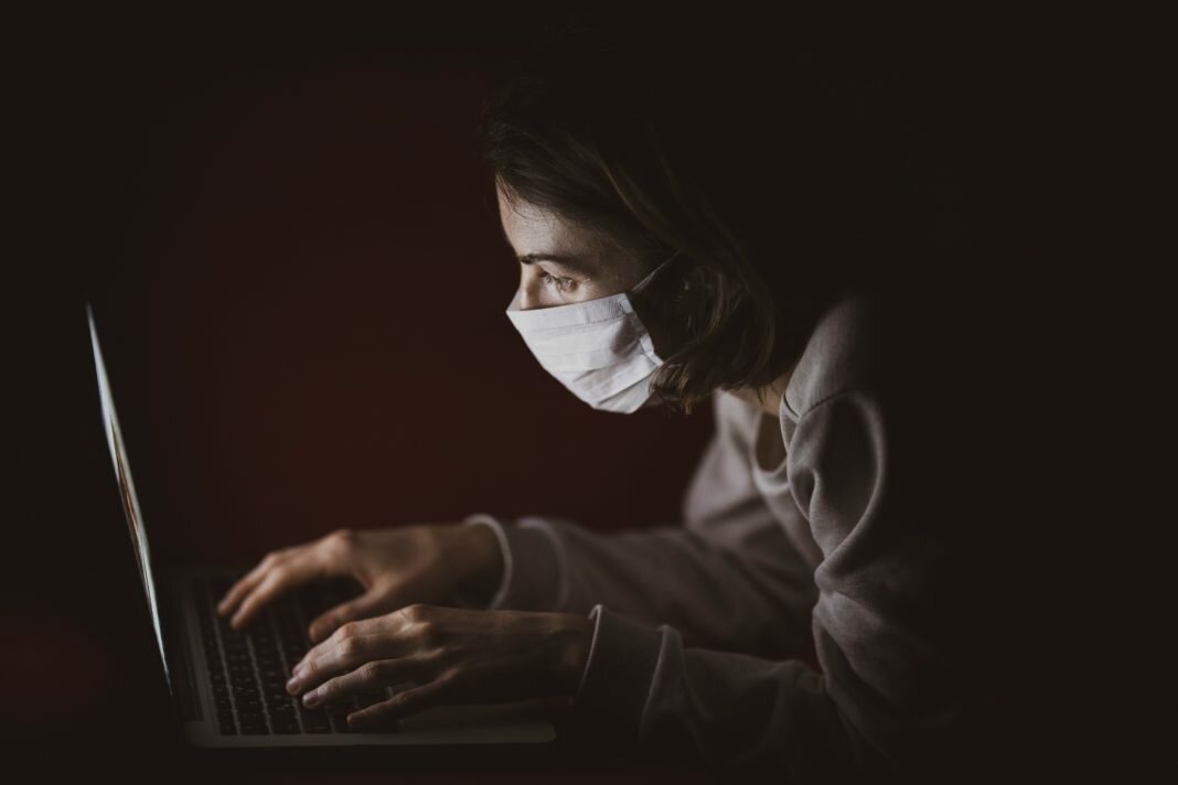 person on laptop in mask