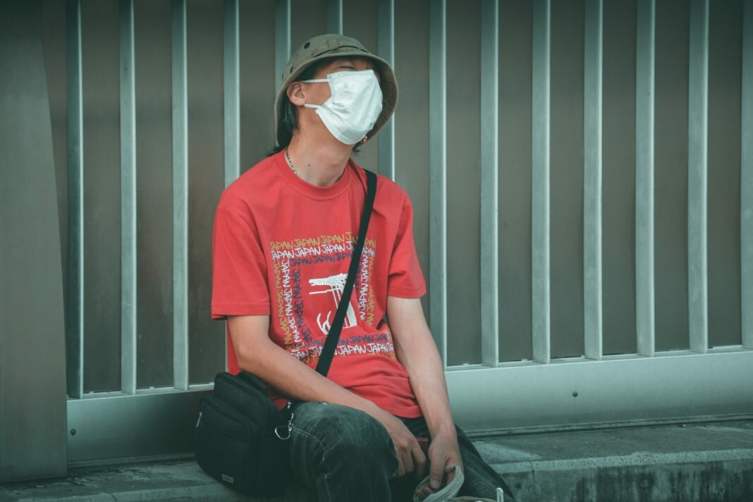 man sitting on street in mask