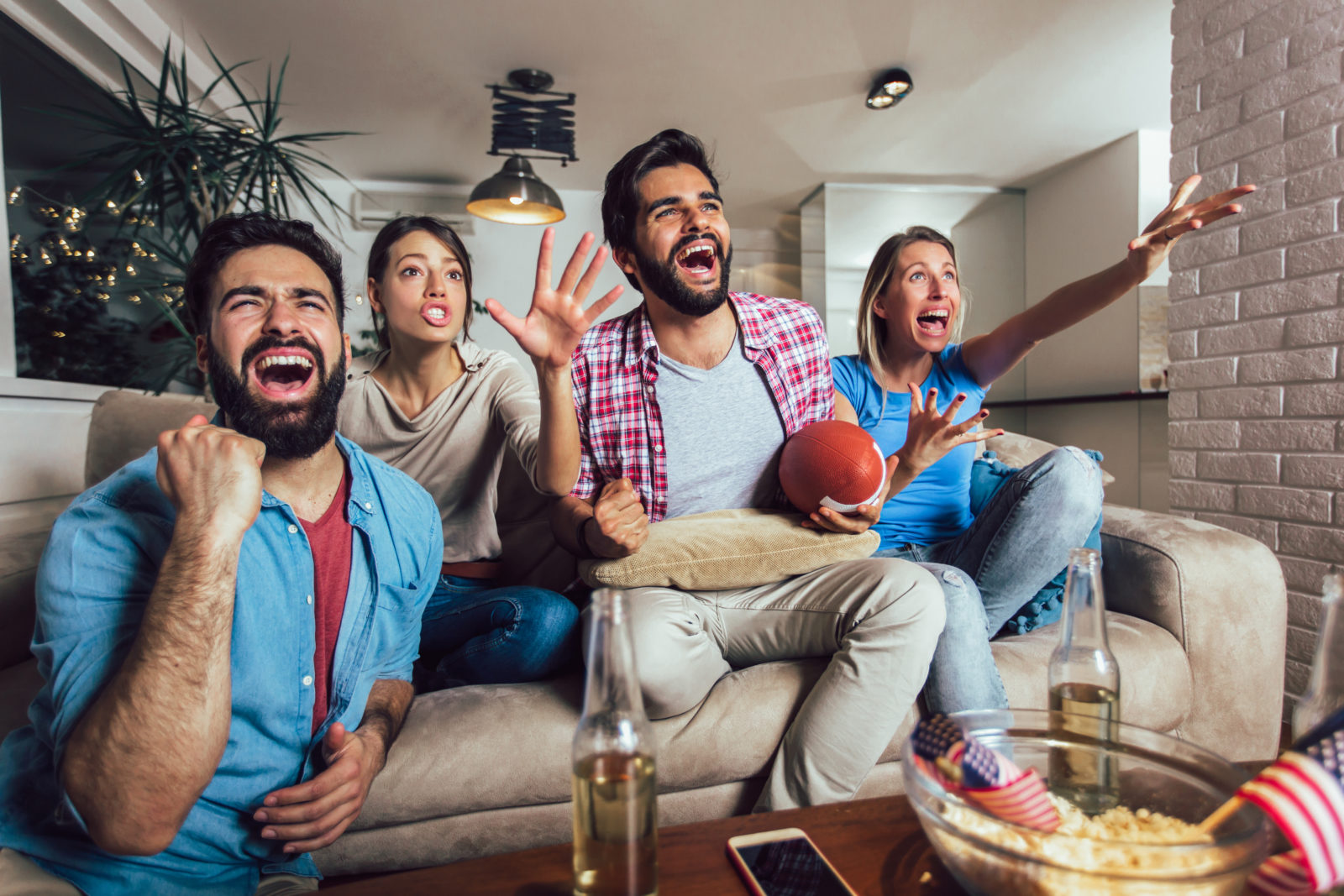 Friends cheering sport league together on tv and celebrating victory at home.Friendship, sports and entertainment concept. 2023/02/AdobeStock_274349745.jpeg 