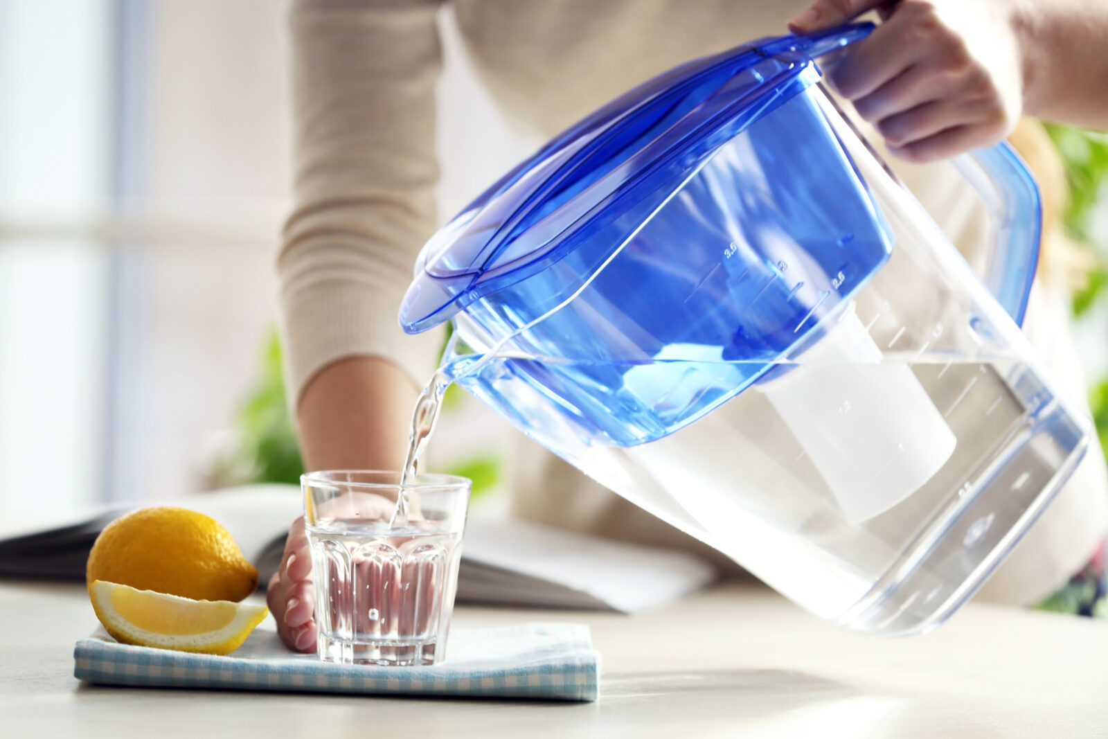 Woman pouring water from filter jug into glass in the kitchen 2023/05/AdobeStock_109078940.jpeg 
