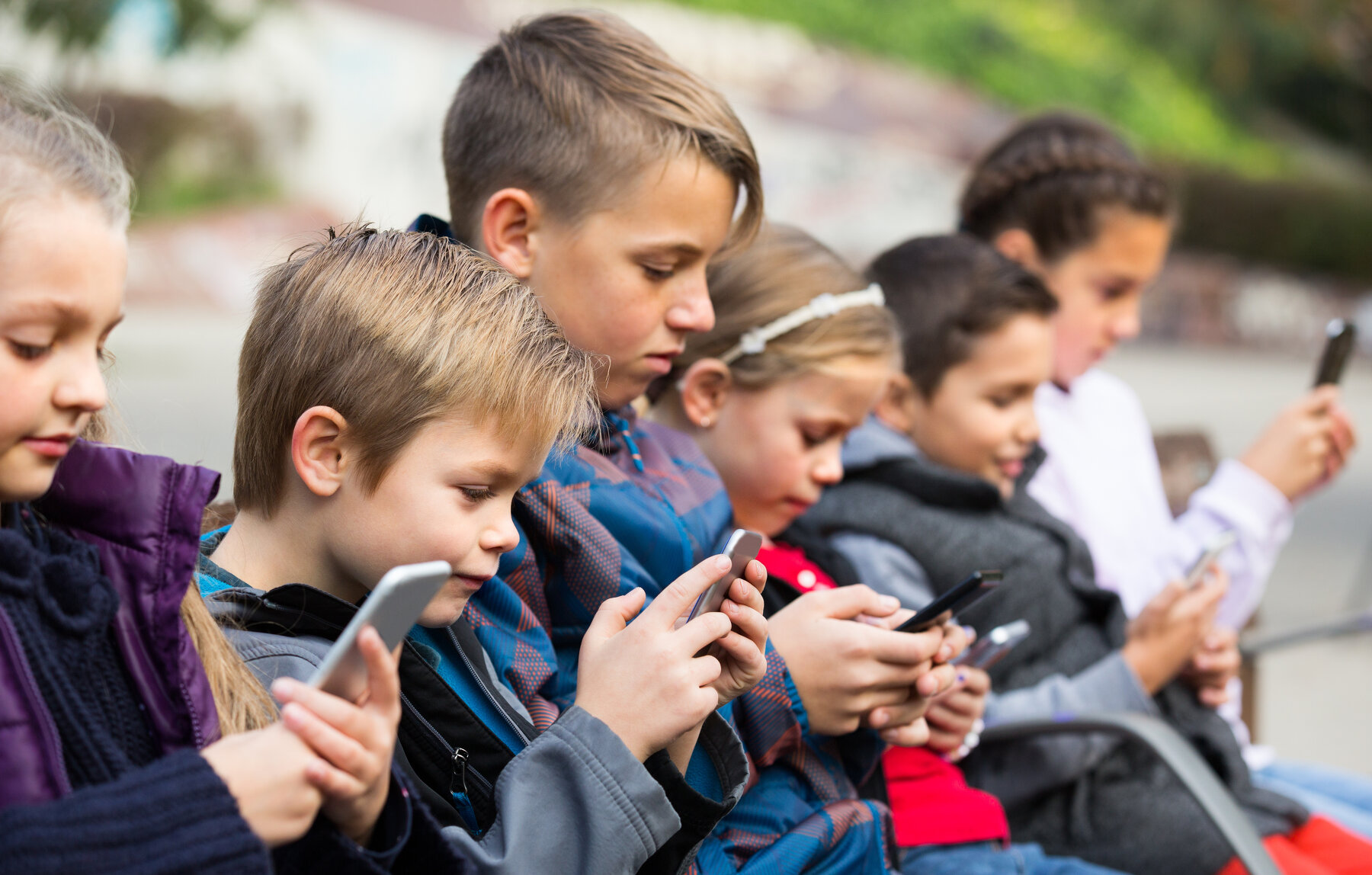Group of caucasian children posing at urban street with mobile devices
