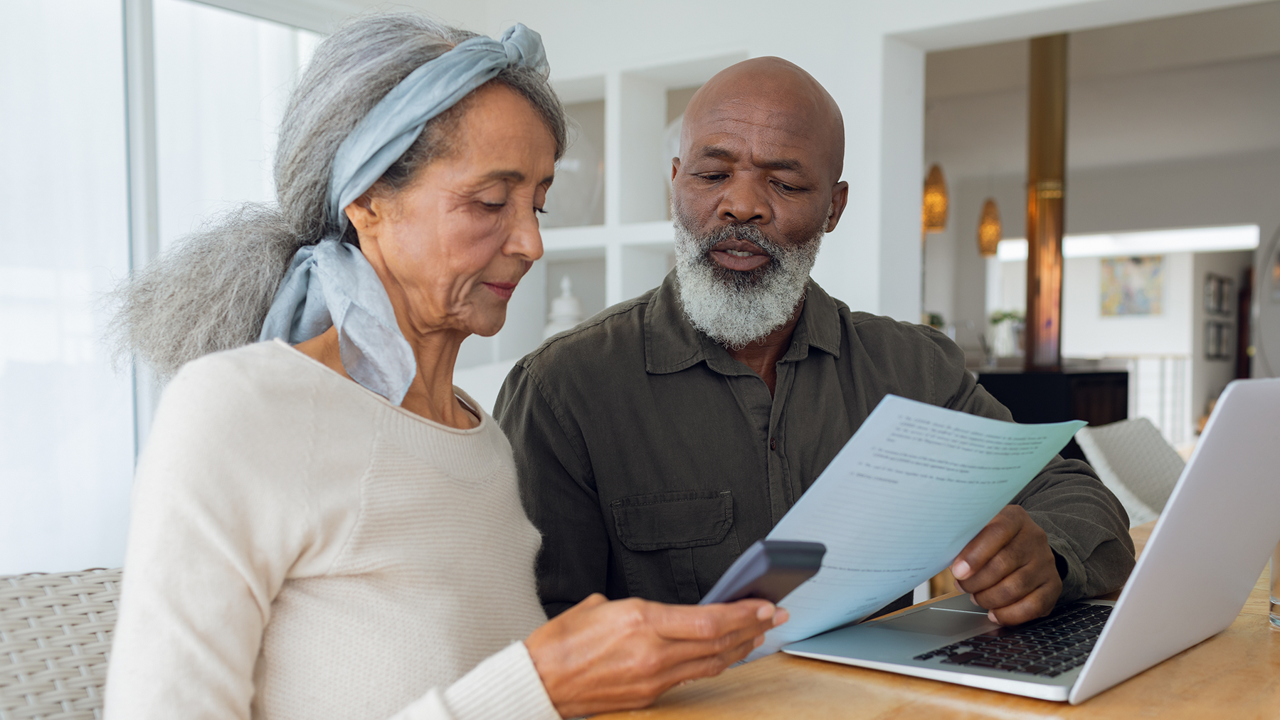 Couple discussing papers and using laptop inside a room