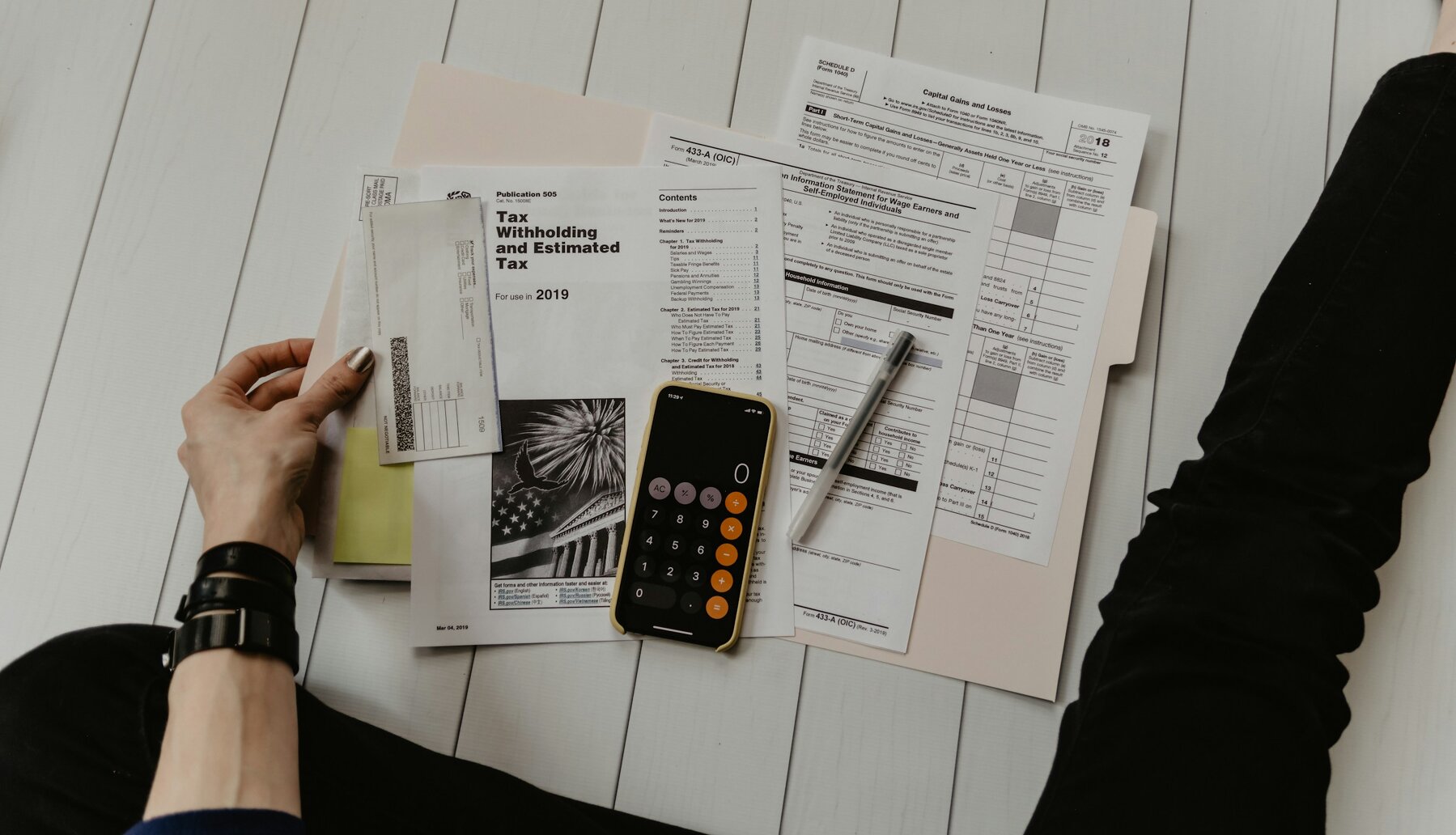 Person sitting on the floor looking at tax documents and a calculator