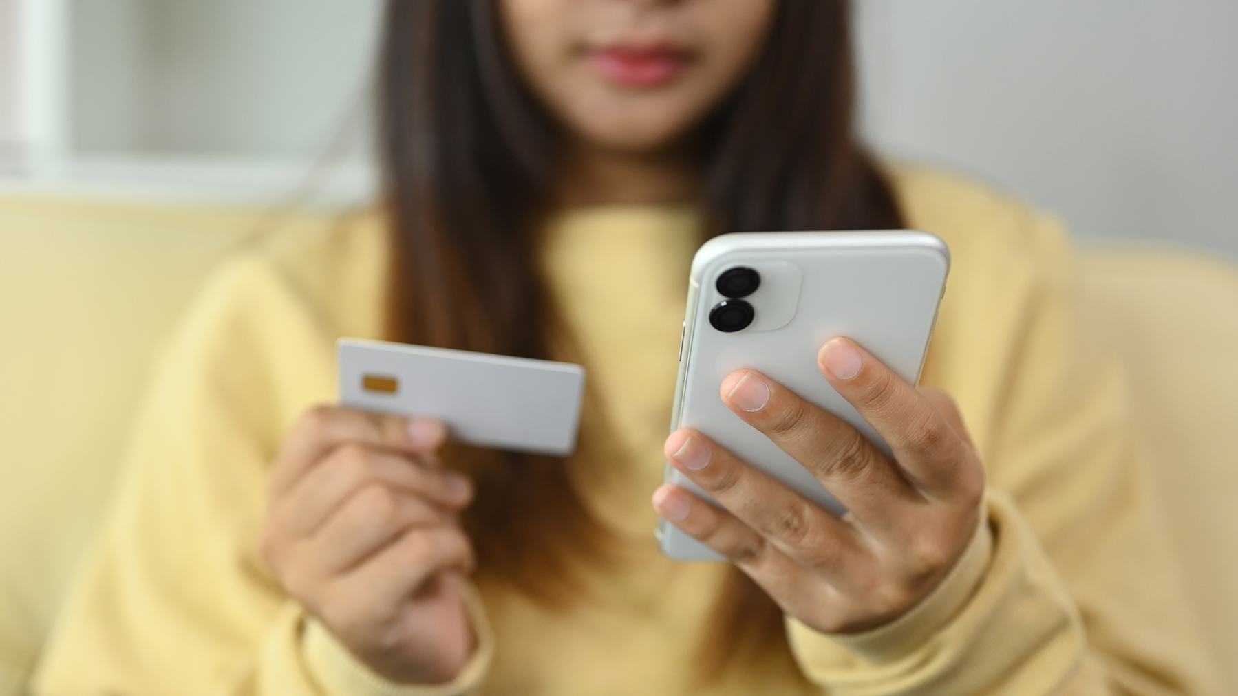 Young woman holding a credit card for online shopping or using mobile banking