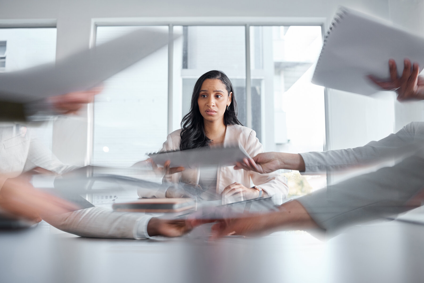 Business woman, anxiety and stress in a meeting or busy office with documents or paperwork. Professional female manager at table with team hands for stress, depression or burnout for deadline crisis.