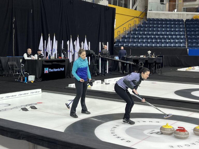 Two people playing curling on ice